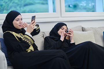 Image showing Portrait of Arabian girls wearing modern abaya using mobile phone