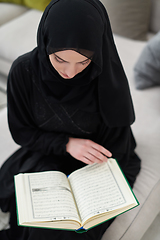 Image showing Portrait of young muslim woman reading Quran in modern home