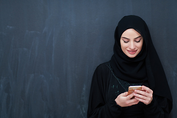 Image showing Young muslim businesswoman in traditional clothes or abaya using smartphone