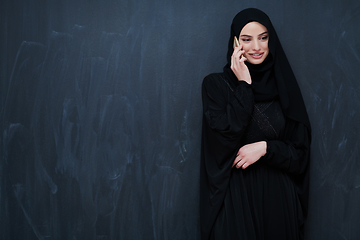 Image showing Young muslim businesswoman in traditional clothes or abaya using smartphone