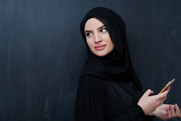 Image showing Young muslim businesswoman in traditional clothes or abaya using smartphone