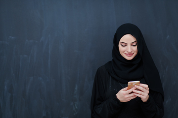 Image showing Young muslim businesswoman in traditional clothes or abaya using smartphone