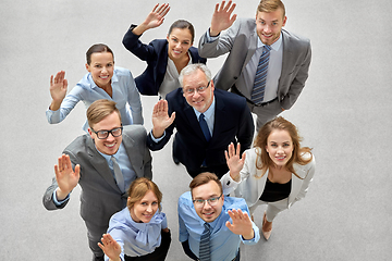 Image showing happy smiling business people waving hands