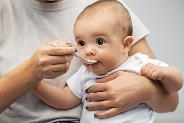 Image showing close up of mother with spoon feeding little baby