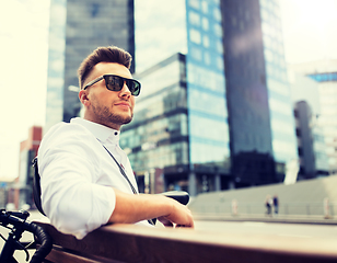 Image showing happy young man with bicycle sitting on city bench