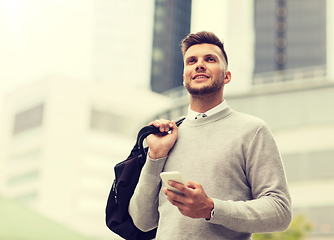 Image showing happy young man with smartphone and bag in city