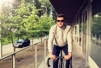 Image showing young man riding bicycle on city street