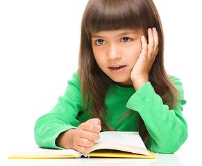 Image showing Young girl is daydreaming while reading book