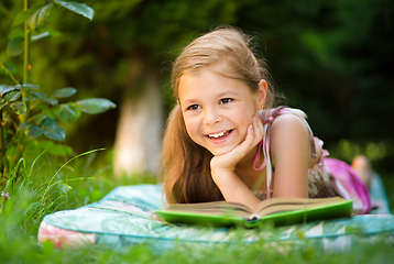 Image showing Little girl is reading a book outdoors