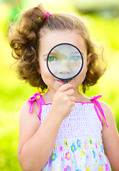 Image showing Little girl is looking through magnifier