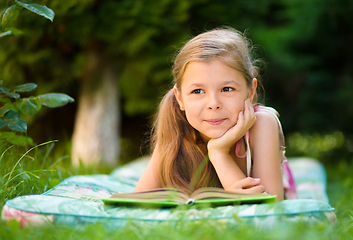 Image showing Little girl is reading a book outdoors