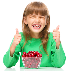 Image showing Cute girl is eating cherries showing thumb up sigh