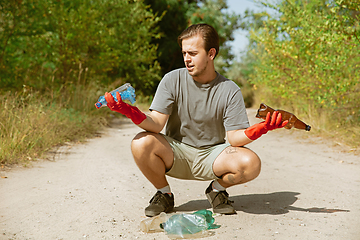 Image showing Volunteer tidying up rubbish on beach