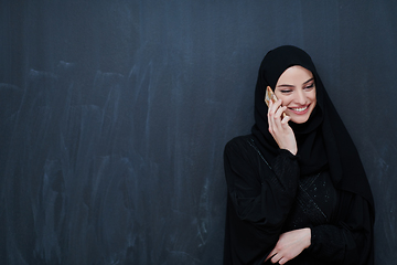 Image showing Young muslim businesswoman in traditional clothes or abaya using smartphone