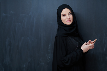 Image showing Young muslim businesswoman in traditional clothes or abaya using smartphone