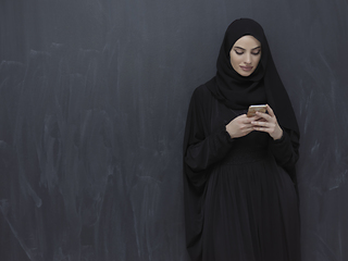 Image showing Young muslim businesswoman in traditional clothes or abaya using smartphone