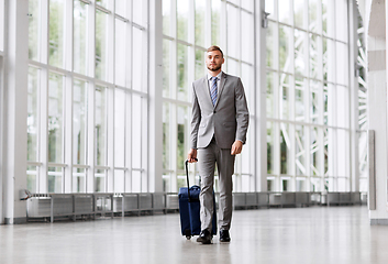 Image showing businessman with travel bag walking along office