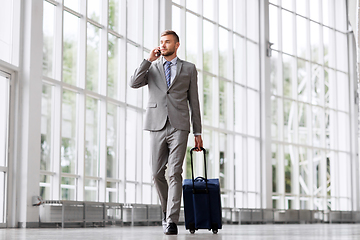 Image showing businessman with travel bag calling on smartphone