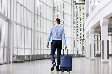 Image showing businessman with travel bag walking along office