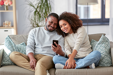 Image showing happy couple with smartphone and earphones at home