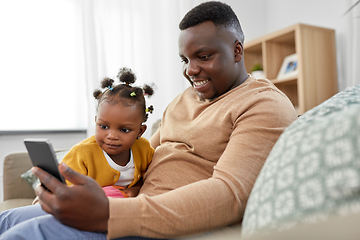 Image showing father with smartphone and baby daughter at home