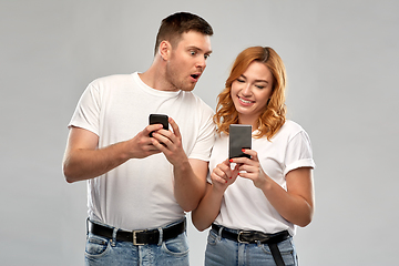 Image showing happy couple in white t-shirts with smartphones