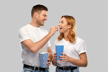 Image showing happy couple in white t-shirts eating popcorn