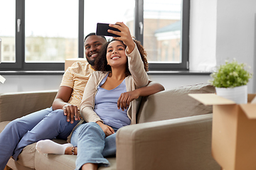 Image showing happy couple moving to new home and taking selfie