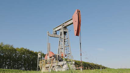 Image showing Operating oil and gas well in oil field, profiled against the blue sky