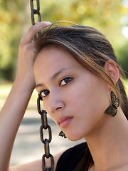 Image showing Young asian american woman holding chain from swing