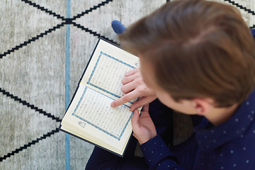 Image showing Young muslim man reading Quran during Ramadan