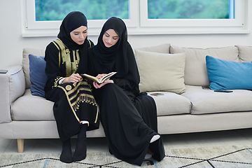 Image showing Portrait of young muslim women reading Quran in modern home.