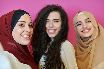 Image showing Muslim women taking selfie by mobile phone isolated on pink background