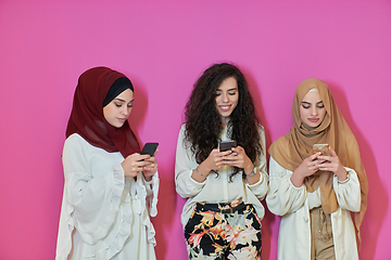 Image showing Muslim women using mobile phones isolated on pink background