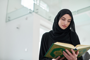 Image showing Portrait of young muslim woman reading Quran in modern home