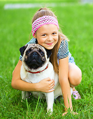 Image showing Little girl and her pug dog on green grass