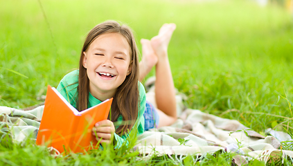 Image showing Little girl is reading a book outdoors