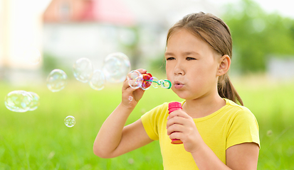 Image showing Little girl is blowing a soap bubbles