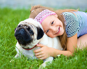 Image showing Little girl and her pug dog on green grass