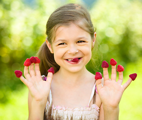 Image showing Young girl is holding raspberries on her fingers