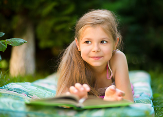 Image showing Little girl is reading a book outdoors