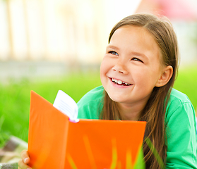 Image showing Little girl is reading a book outdoors