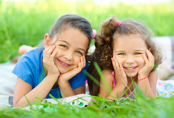 Image showing Two little girls are laying on green grass