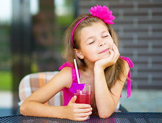 Image showing Little girl is drinking cherry juice