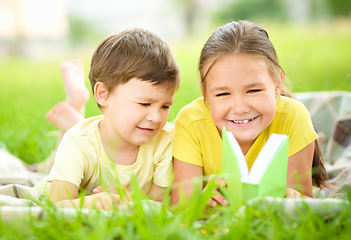 Image showing Little girl and boy are reading book outdoors