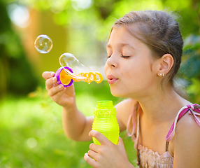 Image showing Little girl is blowing a soap bubbles