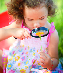 Image showing Young girl is looking at flower through magnifier