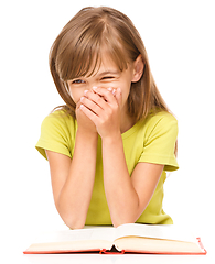 Image showing Cheerful young girl is reading book