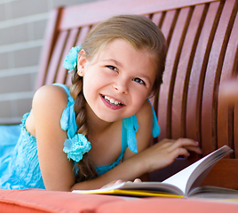 Image showing Little girl is reading a book