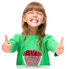 Image showing Cute girl is eating cherries showing thumb up sigh